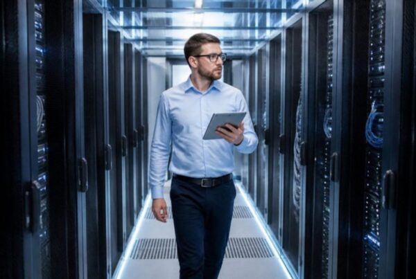 Técnico de un cliente colocation recorriendo el pasillo de racks de un data center con una tablet