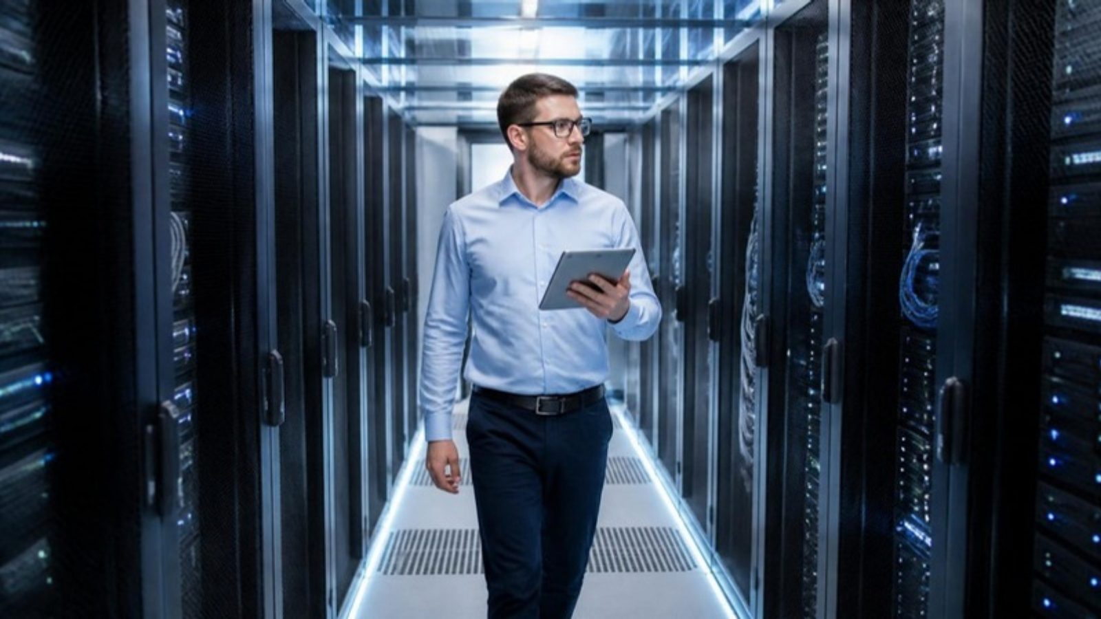 Técnico de un cliente colocation recorriendo el pasillo de racks de un data center con una tablet